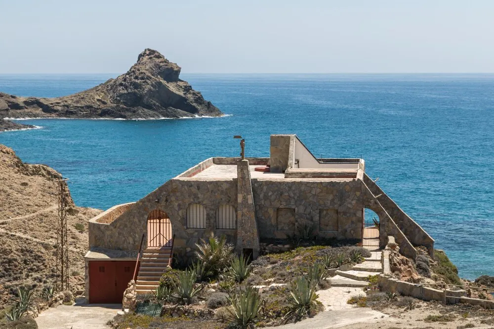Traditionellt stenhus vid Medelhavet med vy mot La Isleta del Moro klippa