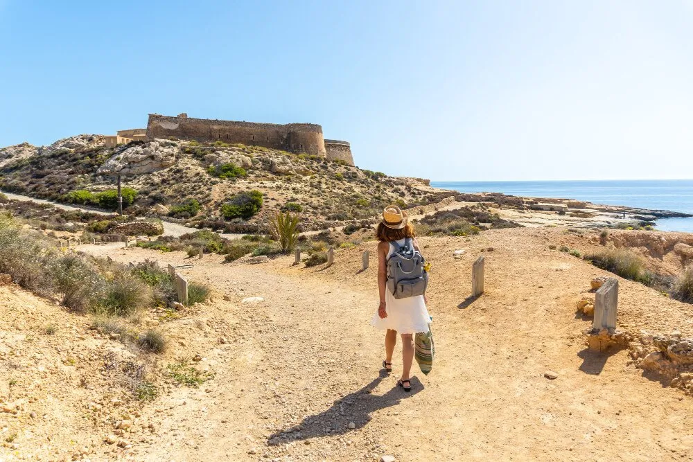 Vandrare på väg mot ett gammalt spanskt fort i Cabo de Gata under solig dag
