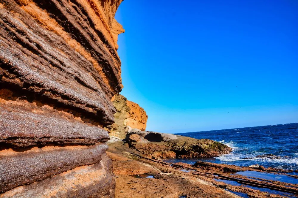 Vulkaniska klippor med orange strimmor vid Cabo de Gatas kust